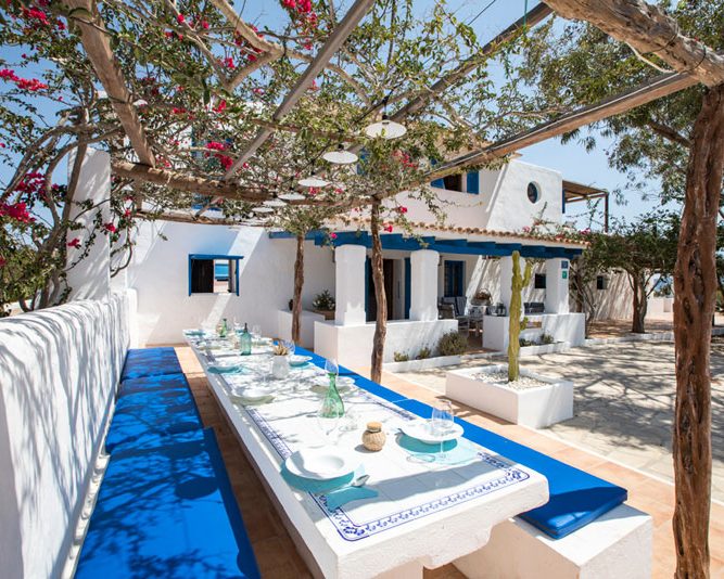 CASA MEDITERRÁNEO Mesa terraza lateral, bajo la enramada de una buganvilla y entrada de la casa