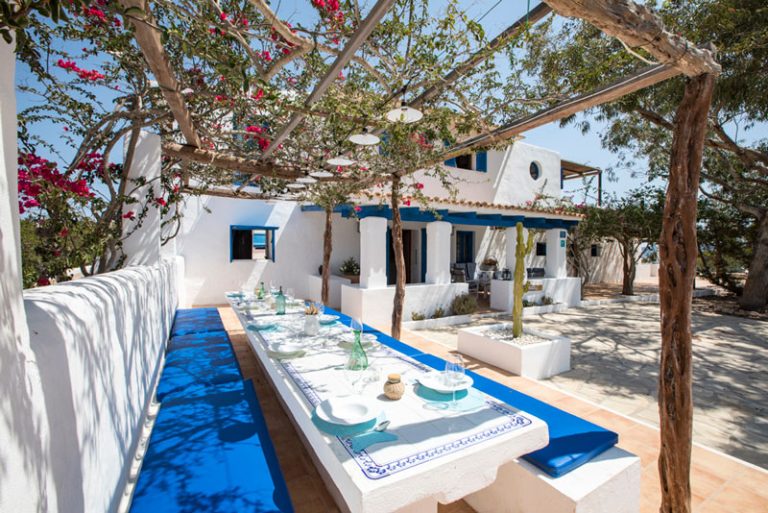 Mesa terraza lateral, bajo la enramada de una buganvilla y entrada de la casa