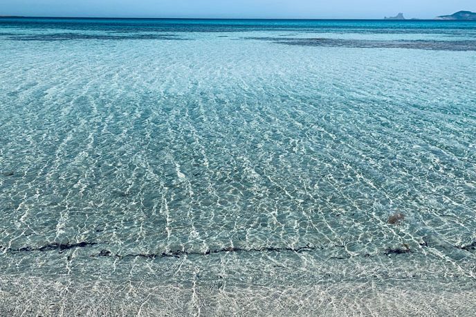 La playa de Illetes Azules turquesa, arena blanca y la isla de Es Vedrà al fondo